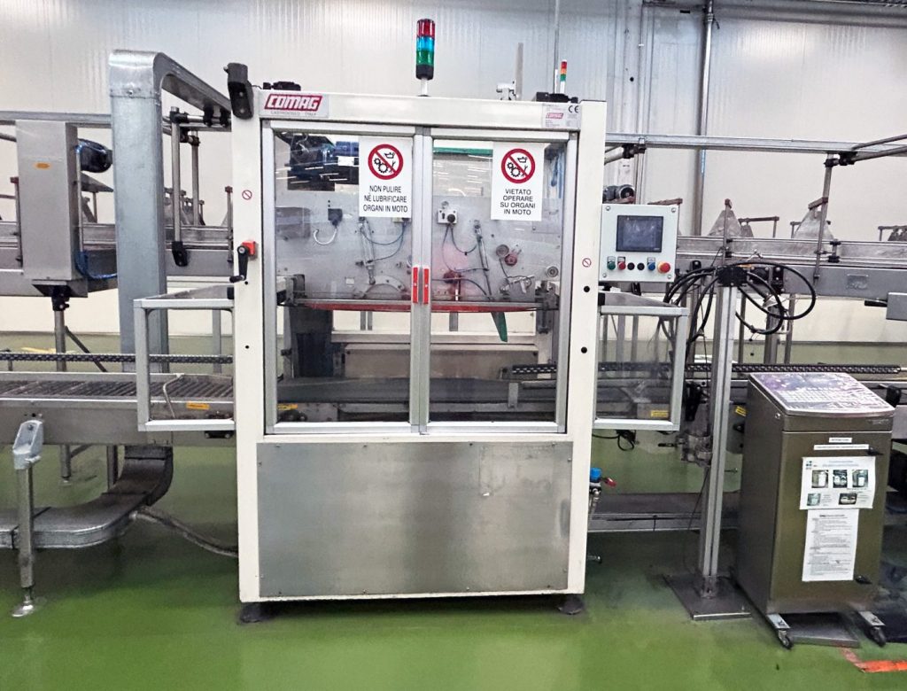 Colocadora de asas COMAG H65/1 (1999), con cambio automático de bobinas, PLC Omron y HMI. Disponible para ver y aprobar o revisada con repuestos compatibles.